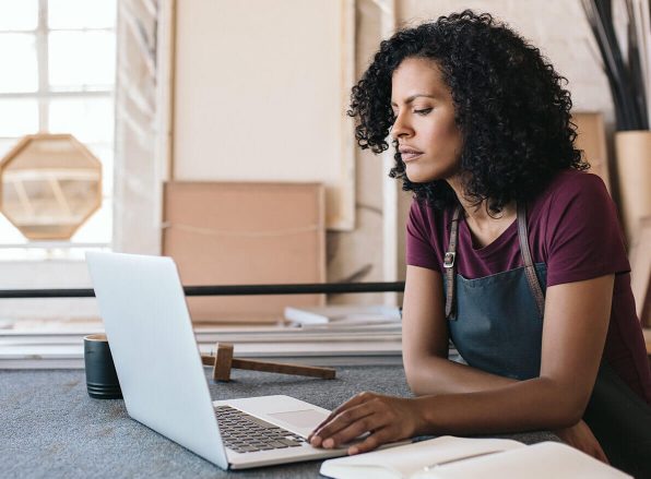 woman with work apron looking at her laptop